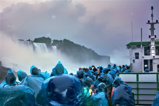 Tourists wearing blue ponchos enjoying a boat tour at Niagara Falls, New York.