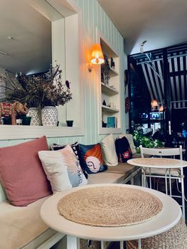 Warm and inviting café interior with comfortable bench seating and decorative pillows.