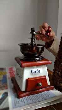 A classic coffee grinder being used by a hand, capturing the essence of vintage coffee making.