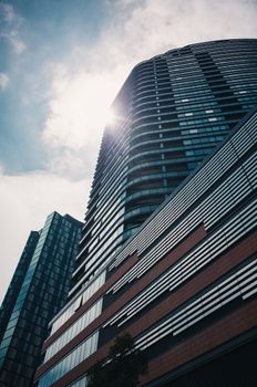 Dynamic low-angle view of modern skyscrapers in a cityscape with dramatic sunlight.