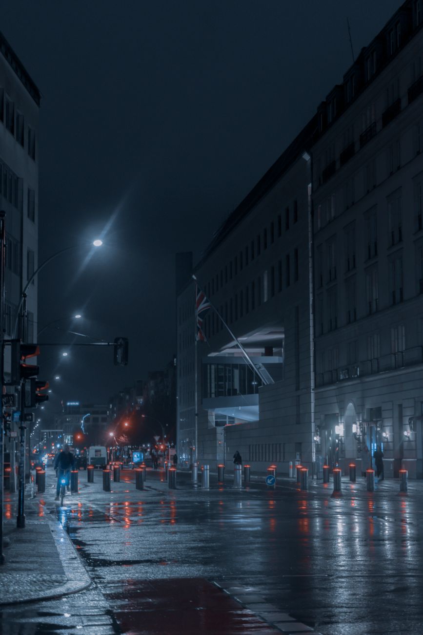 A cinematic view of Berlin's streets at night, reflecting city lights on a rainy evening.