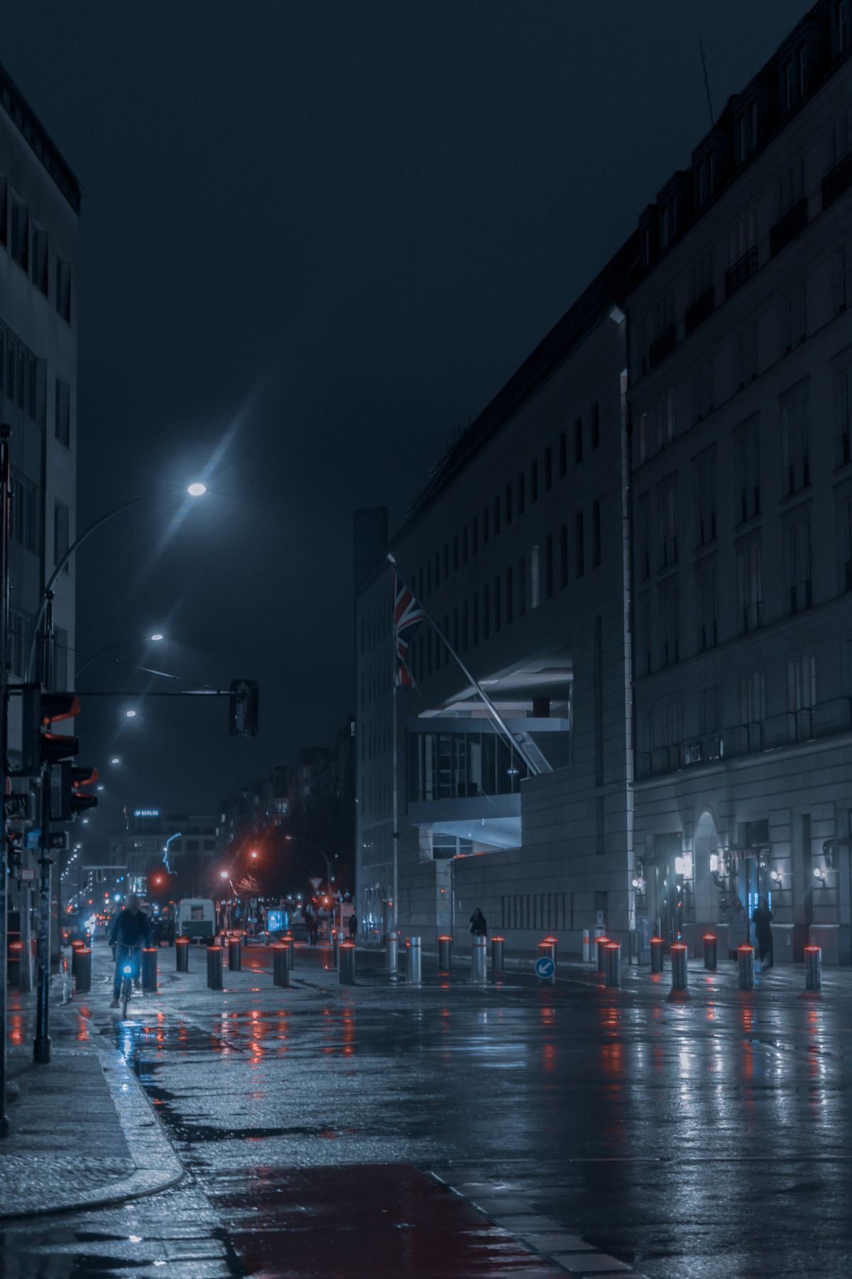 Rain-wet street at night with glowing street lamps