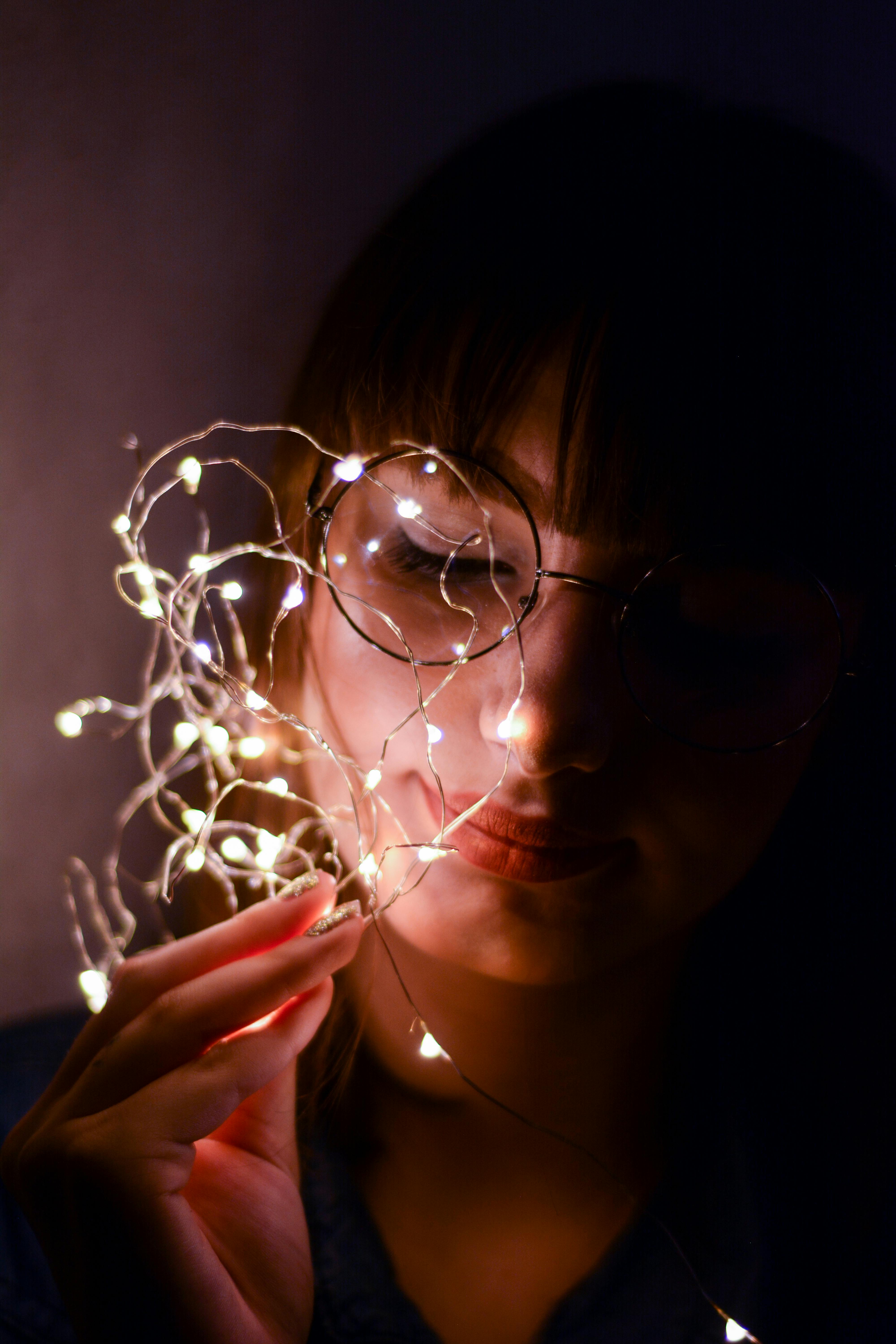 一个女人手持灯串的肖像，营造出喜怒无常又亲密的氛围