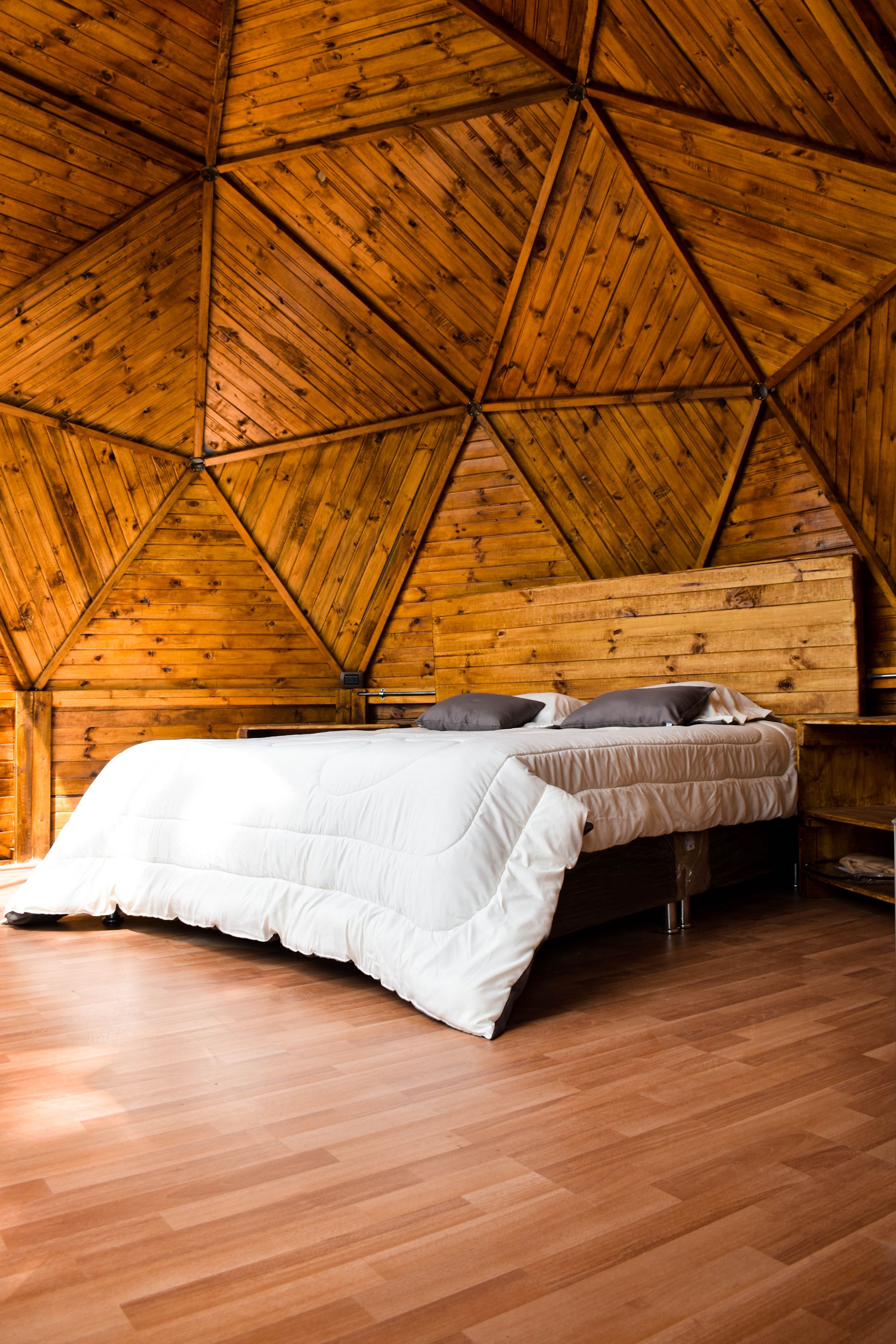 Modern vertical bedroom view with geometric timber walls and a crisp white bed