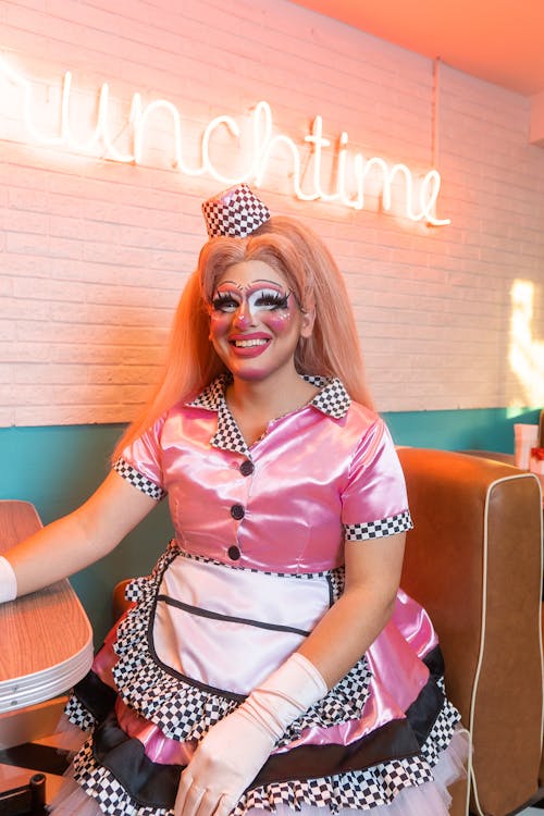 Free Person in a Pink Dress Costume with Apron Sitting in a Bar Stock Photo