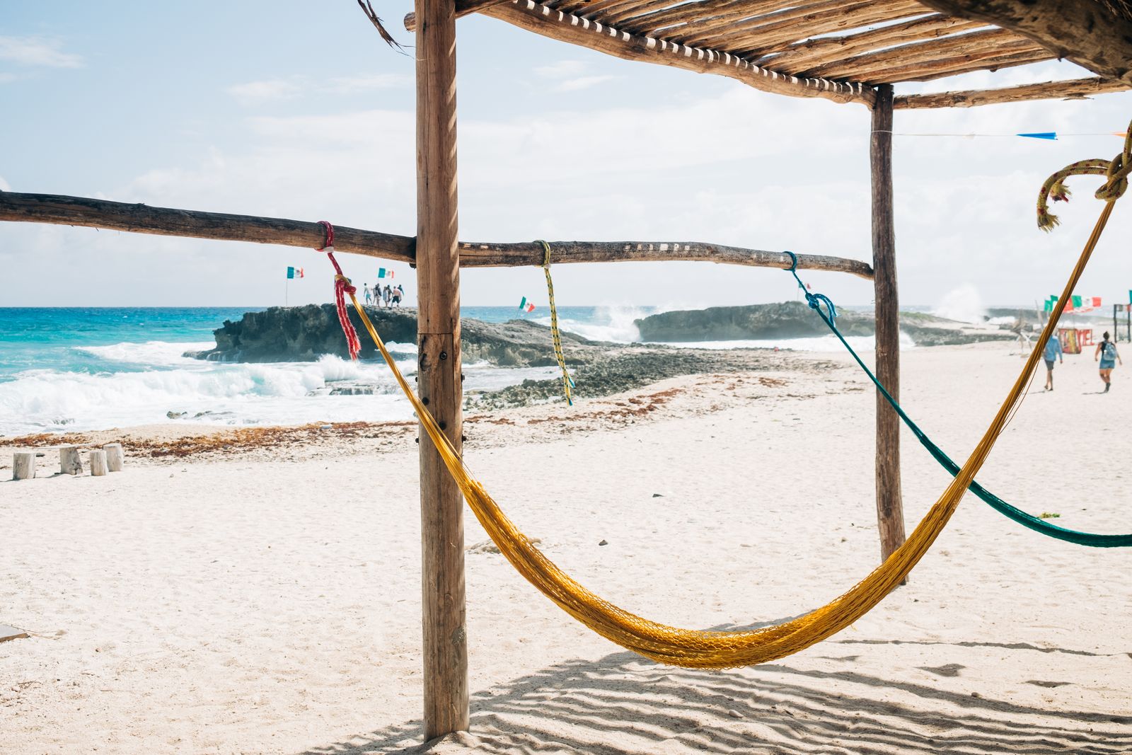 Hammocks arranged on a sandy beach beside the water