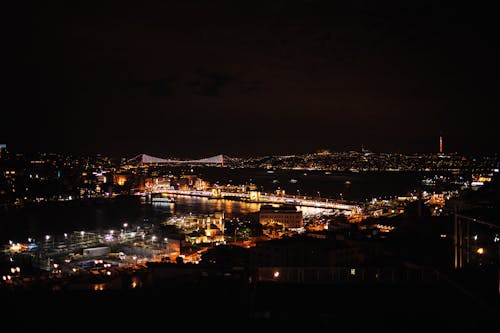 Illuminated Buildings and Bridge above at Night
