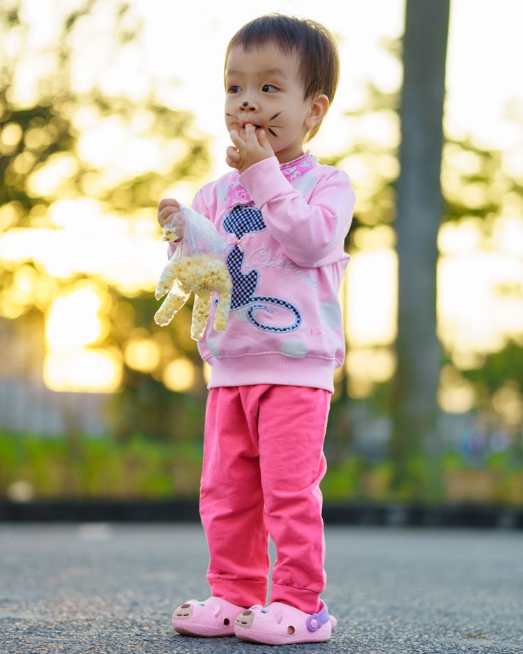 Little Girl With Painted Face Eating Snacks