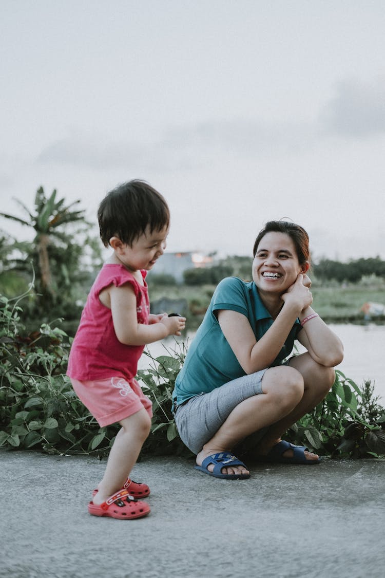 Woman With A Child Laughing At A Riverbank