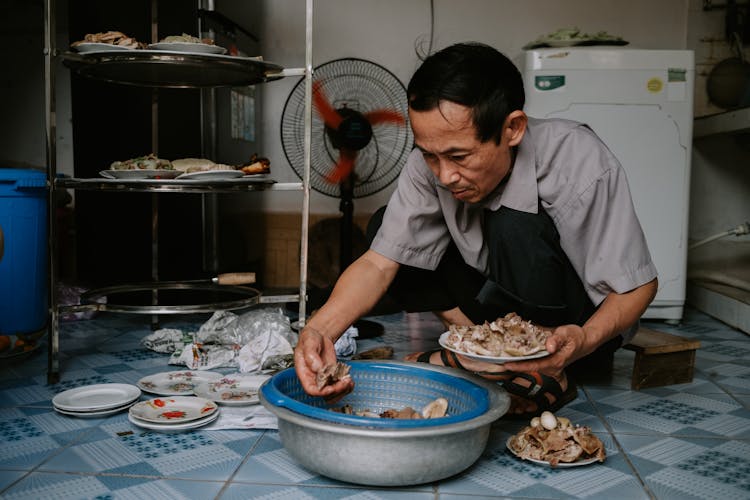 Man Crouching With Food Over Bowls On Floor