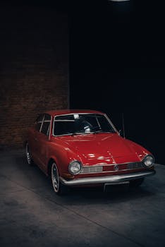 A stunning red vintage car displayed indoors against a dark background.
