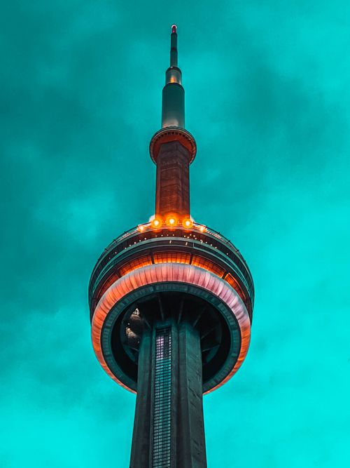 Free A dramatic view of the CN Tower with vibrant green sky, showcasing its illuminated architectural splendor. Stock Photo