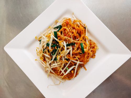 Free Top view of a savory Pad Thai dish garnished with fresh vegetables on a white plate. Stock Photo