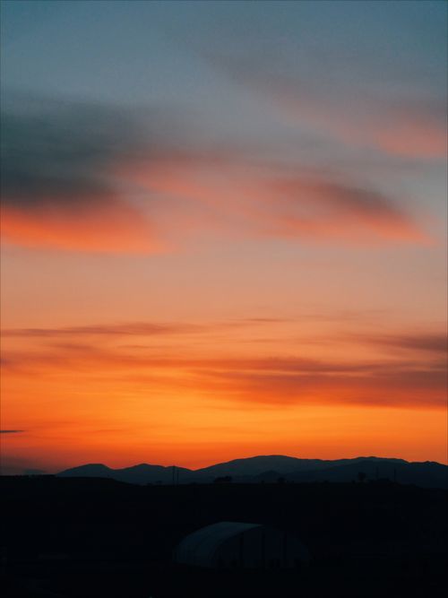 Free Stunning sunset over mountains with dramatic orange and blue sky. Stock Photo