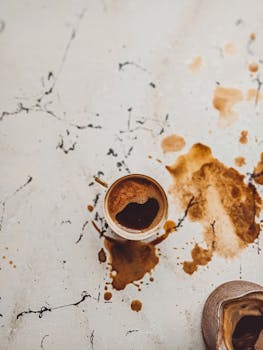 A top view of a Turkish coffee cup with spills on a rustic marble surface.