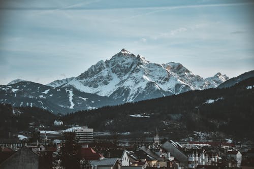 Snow Covered Mountain Near Village Under Blue Sky