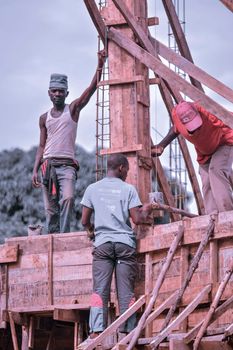 Three construction workers collaborating on a wooden structure outdoors at a building site.
