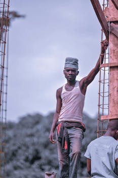 A young man holding steel bars at a construction site, showcasing urban labor.