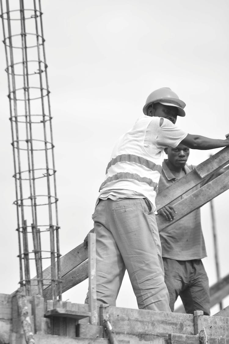 A Man With Helmet Holding A Wood Standing Near A Person