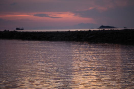 A serene sunset over a calm seascape with vibrant colors and gentle reflections.