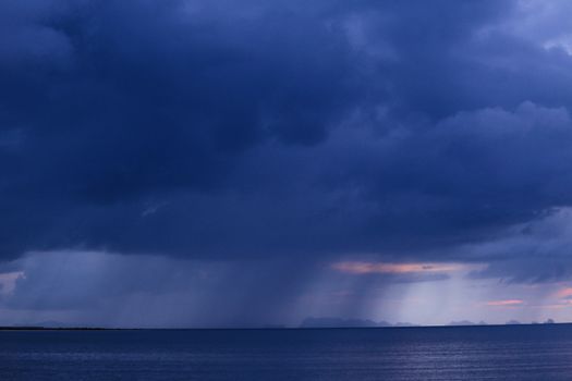 A dramatic and moody overcast sky looms over a calm ocean, creating a striking seascape.