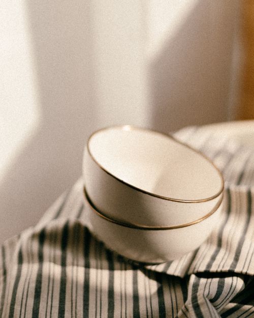Free Close-up of stacked ceramic bowls on striped fabric with soft natural light. Stock Photo