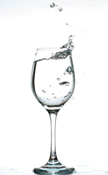 白色背景下，水花溅入酒杯的迷人画面