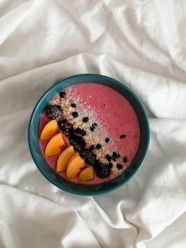 Colorful smoothie bowl with fresh peaches and berries, perfect for a healthy breakfast.