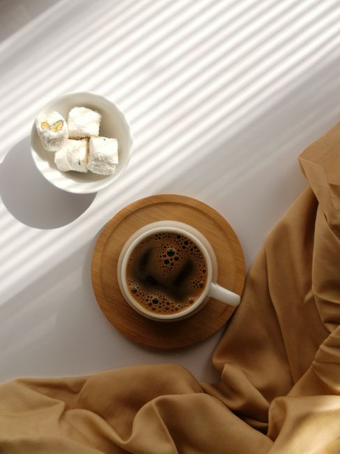 A cozy scene with a cup of coffee and Turkish delight on a light table with soft shadows.
