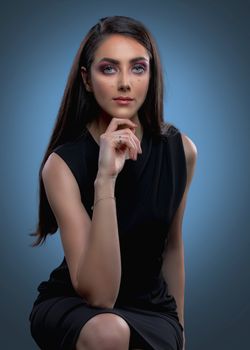 Portrait of a stylish woman posing elegantly in a studio setting.