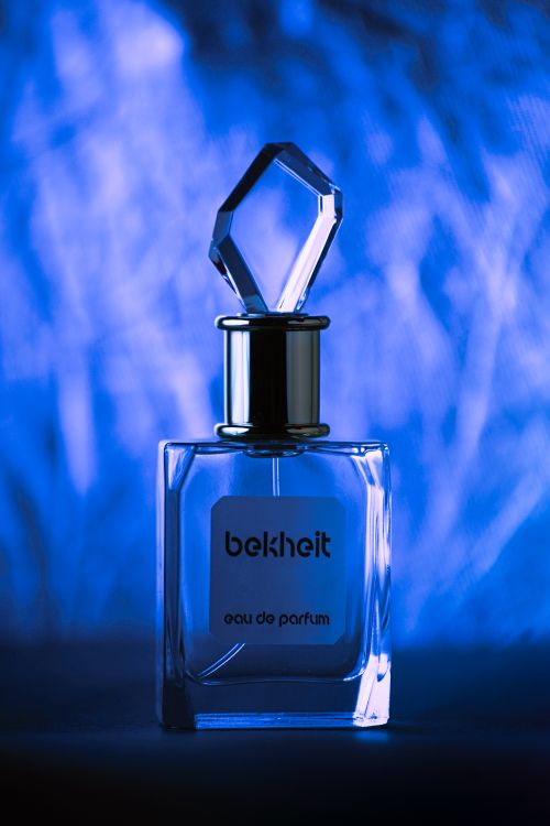 Free A close-up of a glass perfume bottle illuminated by blue light, highlighting its elegance. Stock Photo
