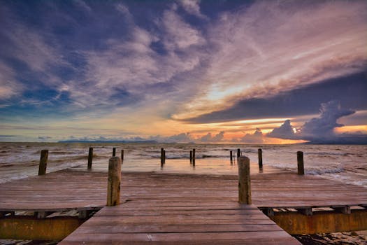 A dramatic sunset over a wooden dock on the coast of Kampot Province, Cambodia.