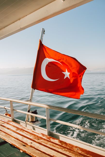 A vibrant Turkish flag flutters on a boat, set against a serene ocean backdrop, embodying travel and adventure.