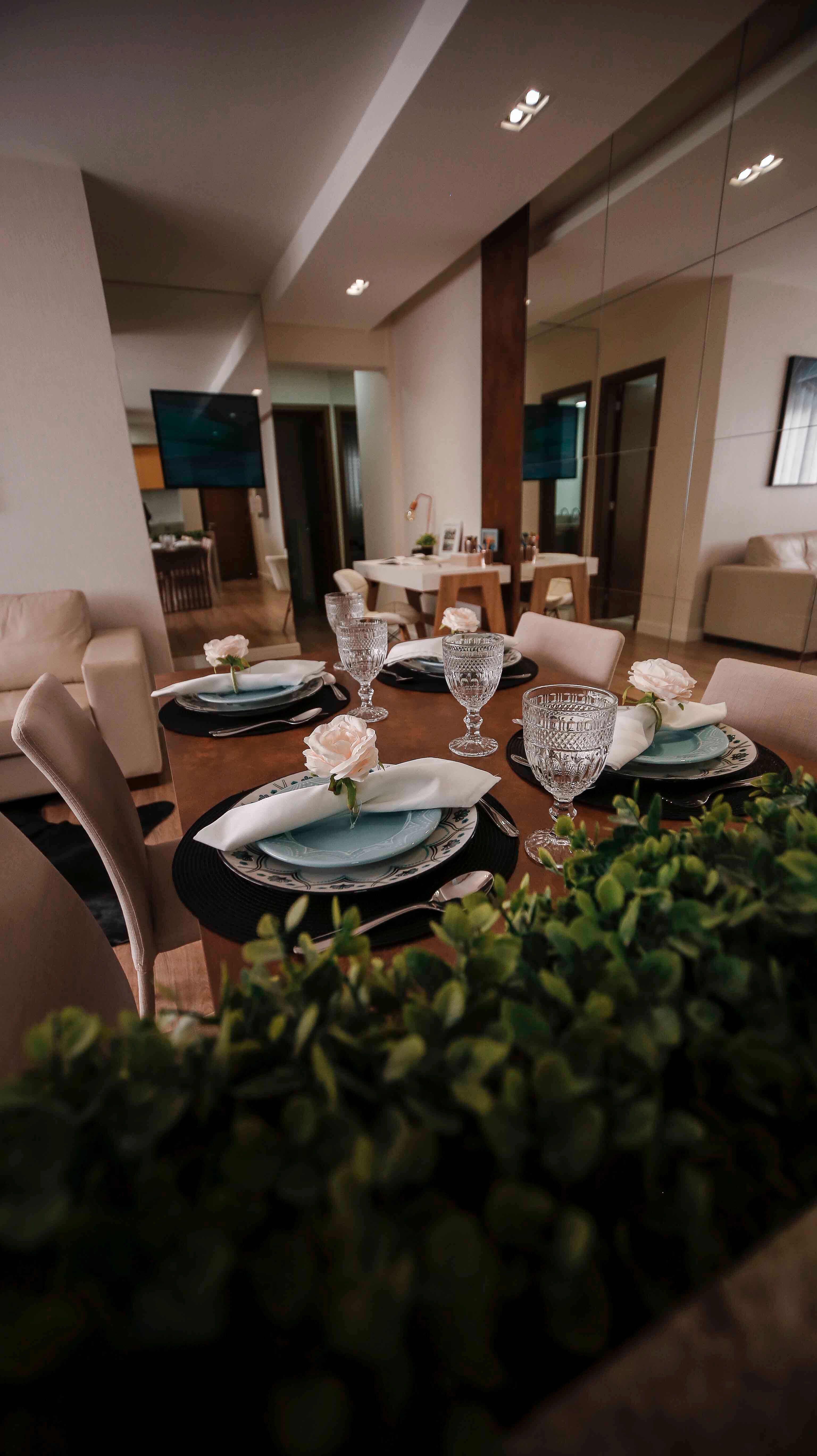 Uma mesa de jantar linda e bem arrumada com louças elegantes e arranjos de flores decorativas em um ambiente interno aconchegante.