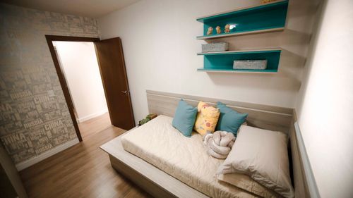Free A well-lit modern bedroom featuring a comfortable daybed, colorful pillows, and decorative shelves. Stock Photo