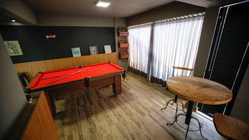 Free Stylish interior design featuring a vibrant red billiard table in a cozy, well-lit room with wooden décor. Stock Photo