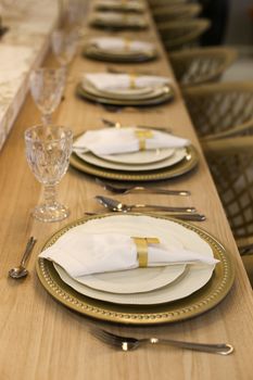 Elegant table setting with crystal glasses and golden plates on a wooden table.