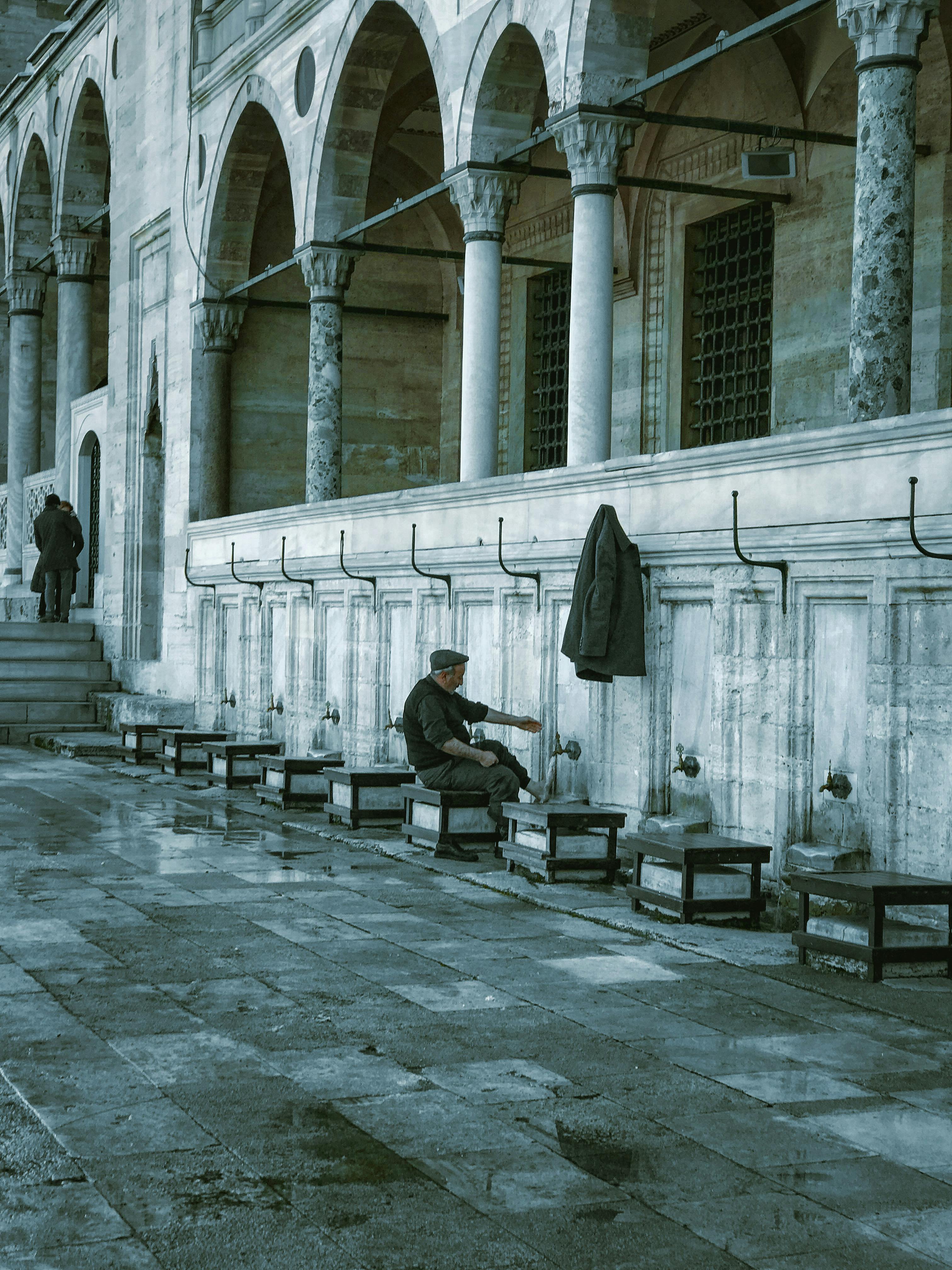 A man performs ablution at a historic mosque, reflecting religious rituals and architectural beauty.