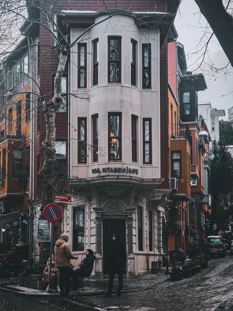 A Group Of People Infront Of A Building Beside The Street