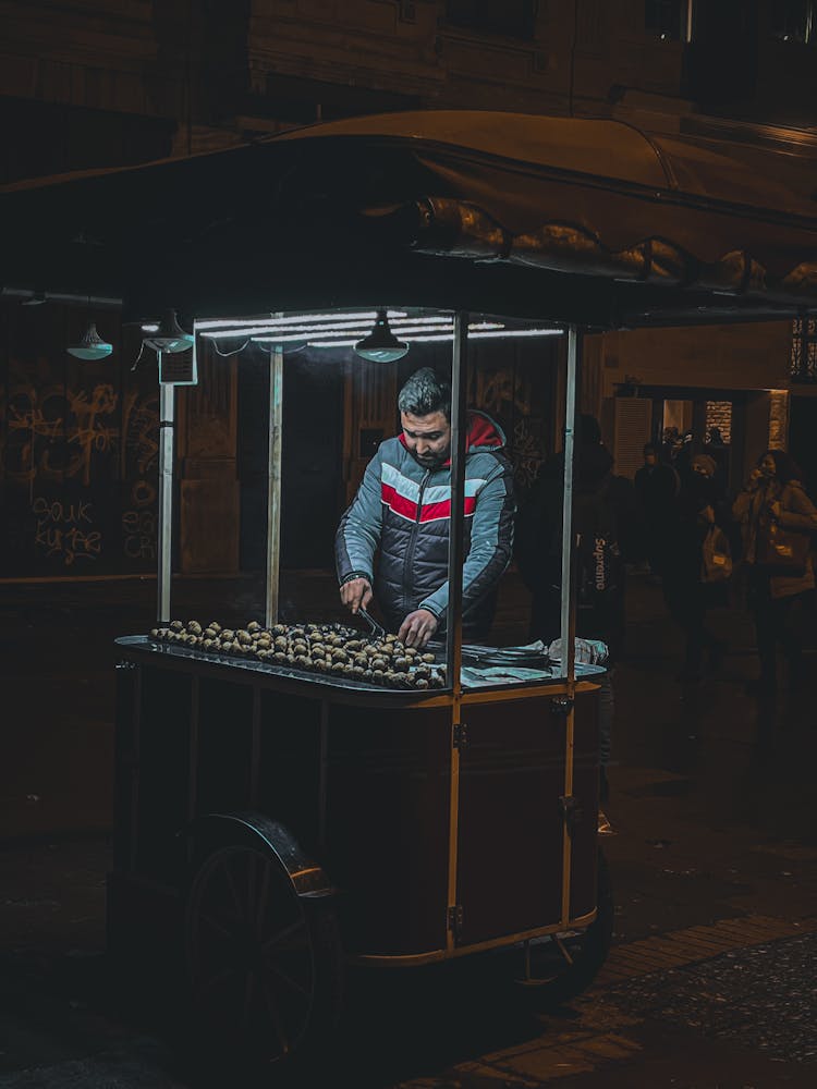 Dark Image Of A Man Selling Sweets From A Cart At Night