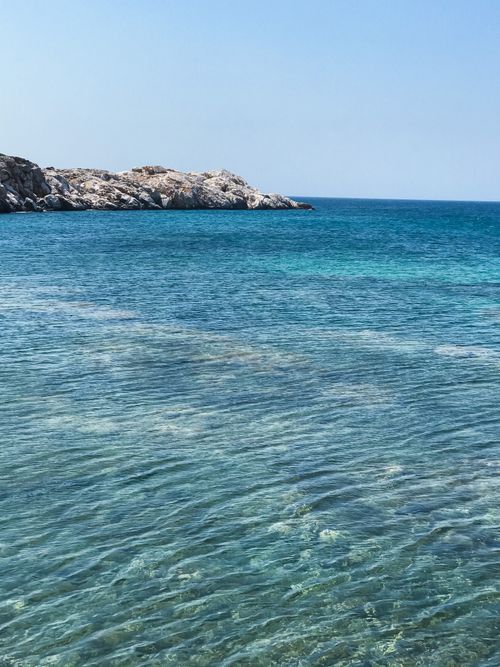 Free Pristine seascape with clear blue water and rocky shoreline under a sunny sky. Stock Photo
