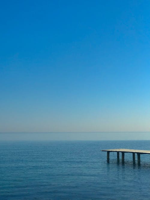 Brown Wooden Dock on Blue Sea Under the Blue Sky
