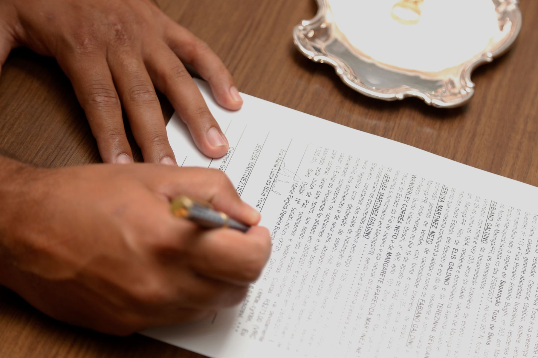 A person signing a document with a pen