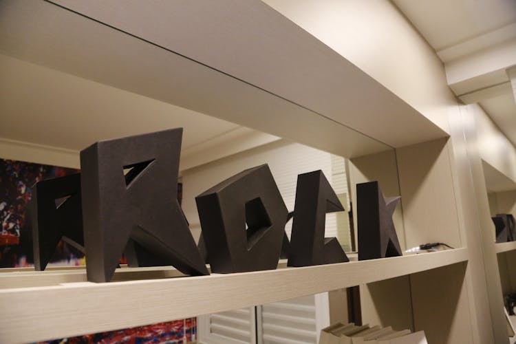 A Black Letter Design On A Wooden Shelf 