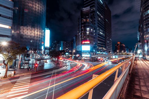 Long exposure shot capturing city lights and traffic flow in a busy downtown district at night.