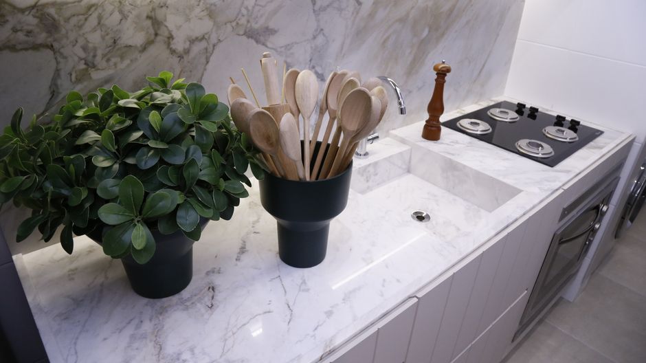 Sleek minimalist kitchen with marble counter, wooden spoons, potted plant, modern fixtures, and stovetop. - 8 Smart Kitchen Organization Tools That Keep Countertops Clutter-Free