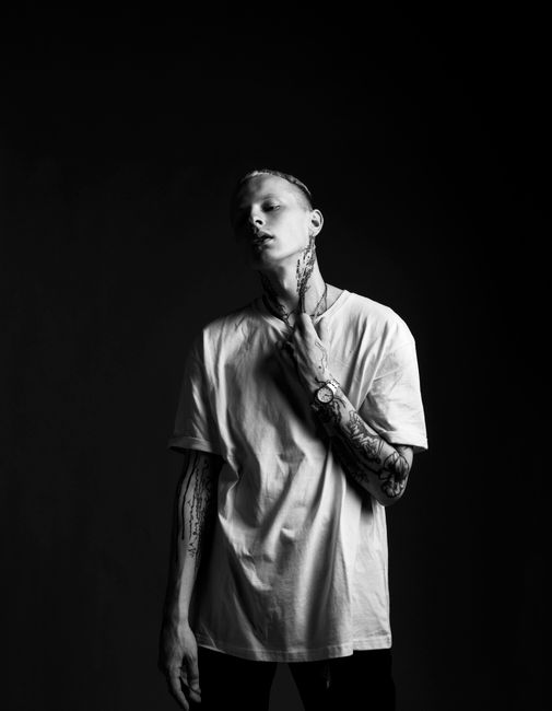 Artistic black and white portrait of a tattooed male model wearing a white shirt.