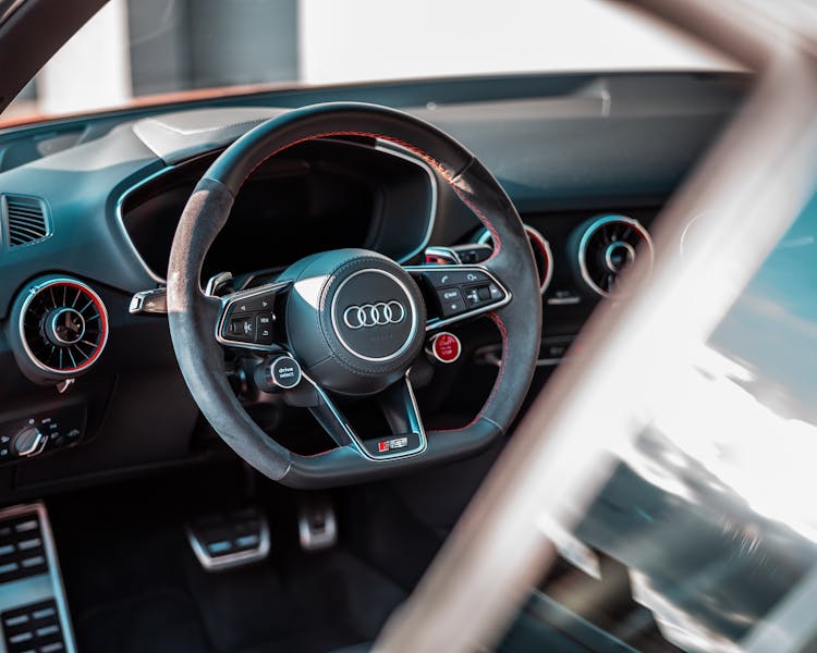 A Black Steering Wheel Of A Car With Brand Logo