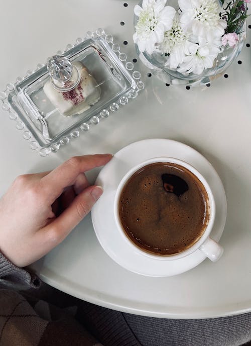 A Person Holding White Ceramic Cup With Brown Liquid