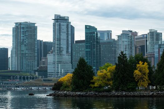 Beautiful skyline of Vancouver with autumn foliage and water reflections.